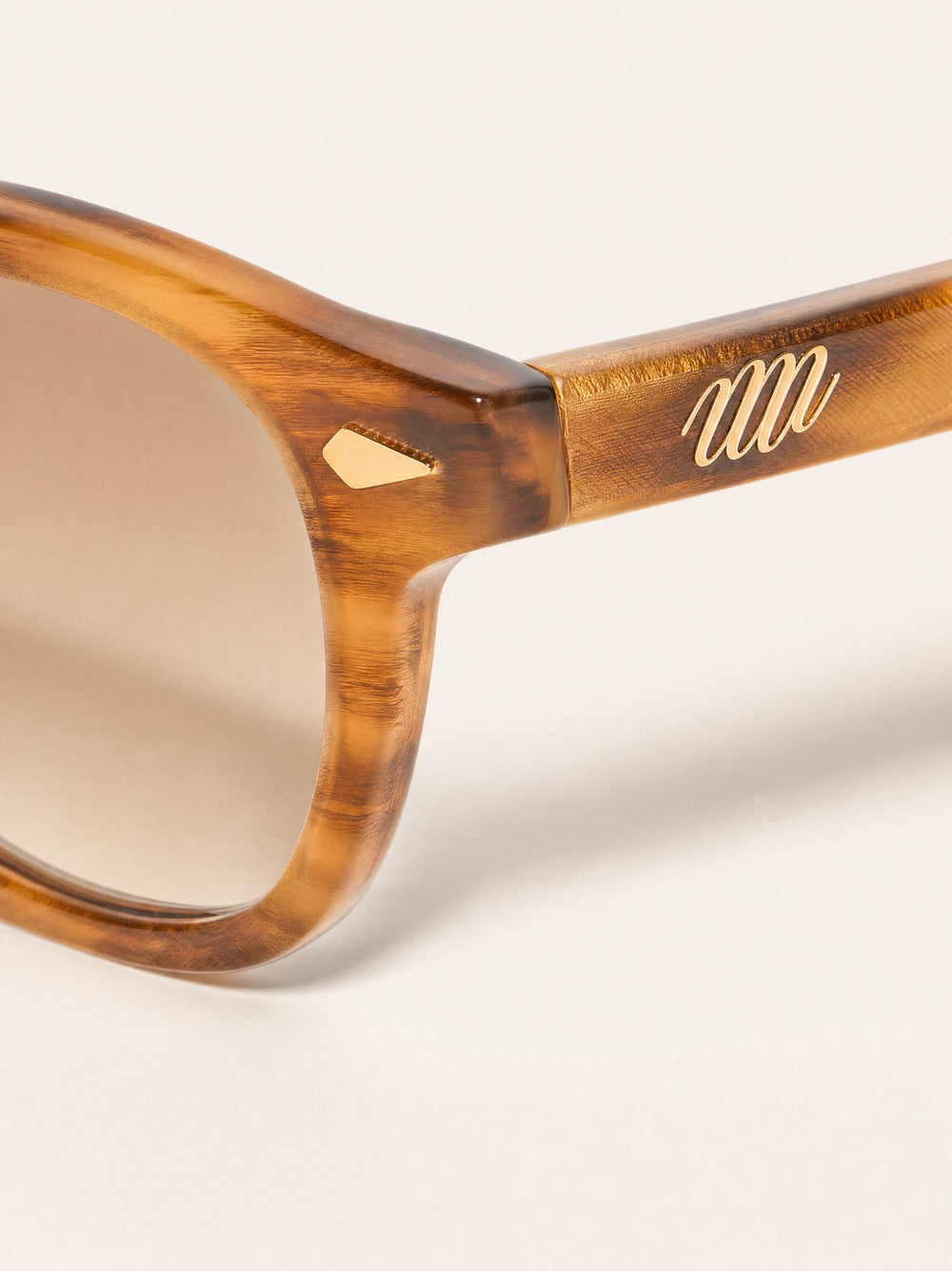 Close-up of Nour gradient lens and gold mair emblem on the temple